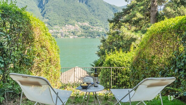 A terrace with two chairs and a table, overlooking a lake with a mountainous backdrop. - OC Lake Love in Laglio (Laglio)