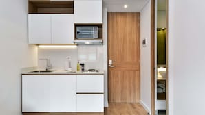 A compact kitchen with white cabinetry, a built-in microwave, and a wooden door leading to a bathroom. - w Radiant Loft w Amazing Terrace in Bogota (Bogotá)