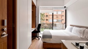 A modern hotel room with a large bed, a desk, and a view of the cityscape. - w Radiant Loft w Amazing Terrace in Bogota (Bogotá)