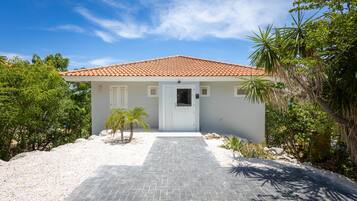 A single-story house with a tiled roof, a white door, and a paved driveway leading to the entrance.