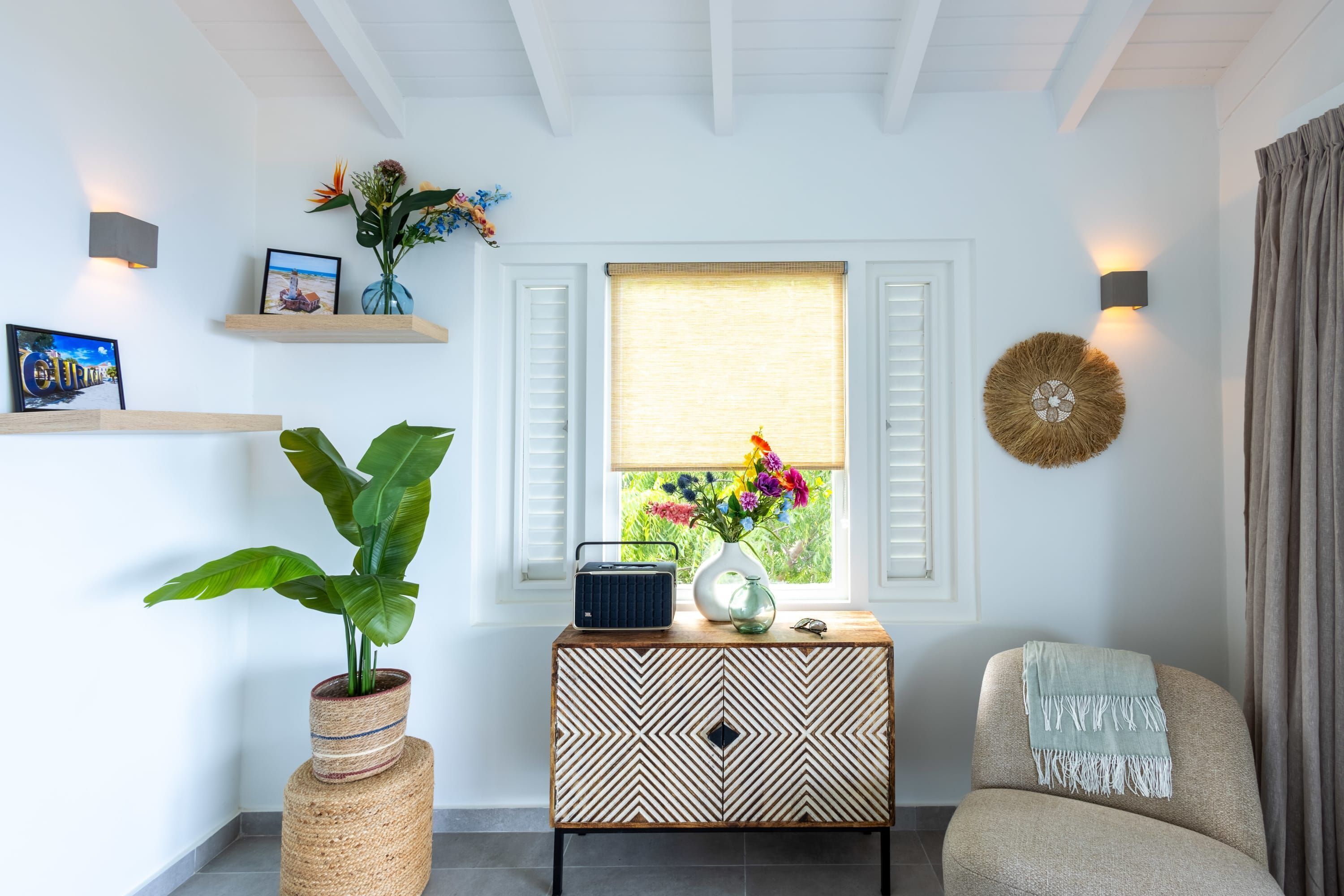 Une pièce avec une fenêtre, une plante, une radio et un élément décoratif mural.