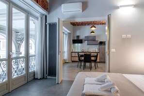 Ein modernes Hotelzimmer mit einem großen Bett, einem Essbereich und einer Küche im Hintergrund.
