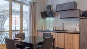 A modern kitchen with a dining area, large windows, and a brick ceiling. - Queen Apartment in Torino (Turin)