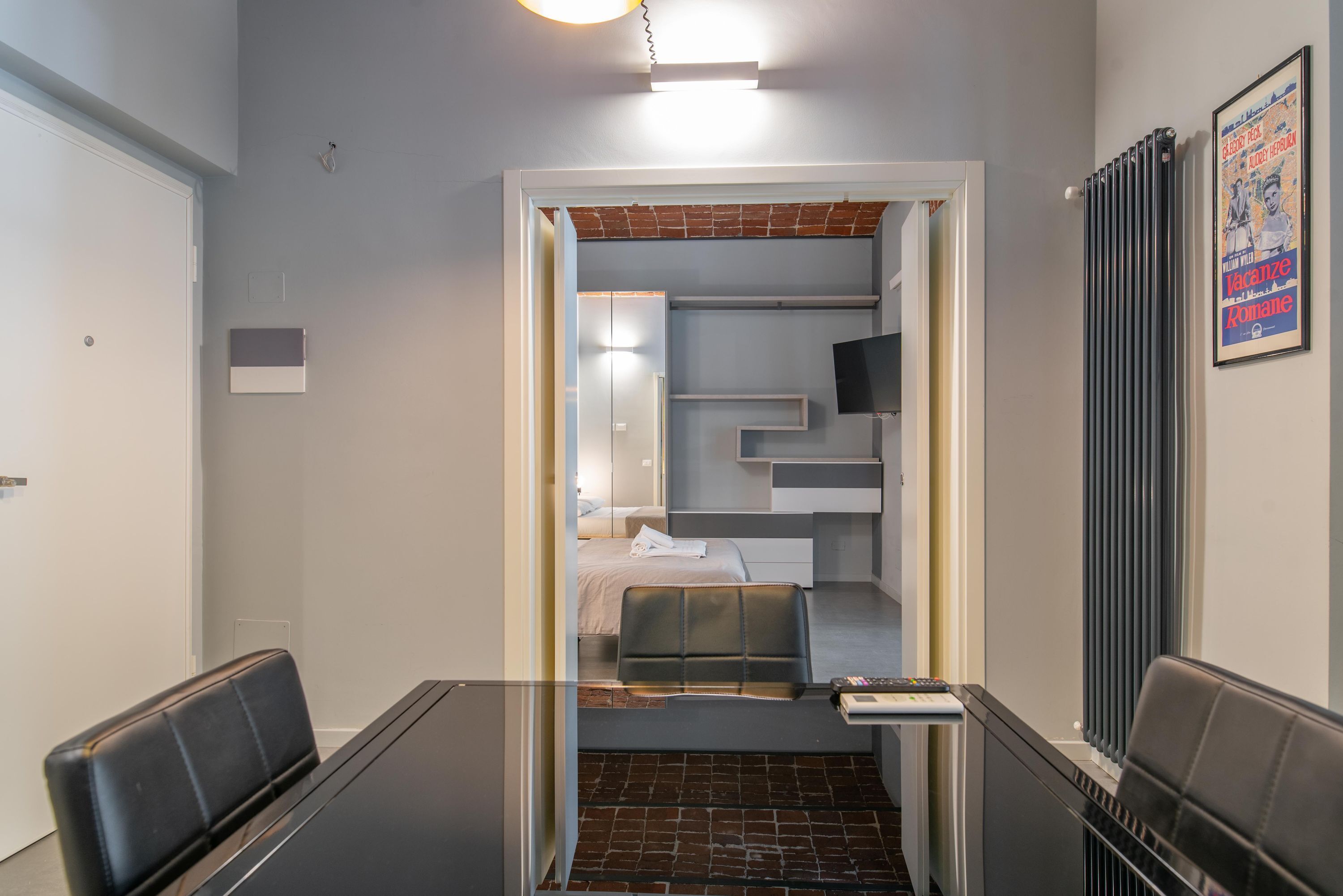 Een moderne hotelkamer met een glazen tafel, een bed met hoofdeinde, een televisie en een radiator.