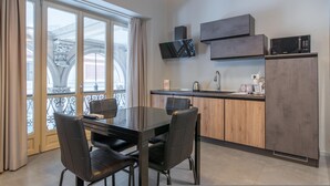 A modern kitchen with a dining area, featuring a large window, a flat-screen TV, and built-in appliances. - Queen Apartment in Torino (Turin)