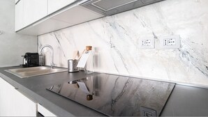 A modern kitchen with a marble backsplash, stainless steel sink, and a coffee maker. - Italianway Comfort - Fara 29 (Milan)