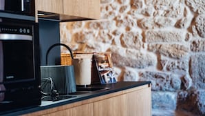 A kitchen with a microwave, a kettle, and a basket on the counter.