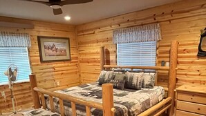 Een slaapkamer in blokhutstijl met een bed, een bankje en een dressoir.