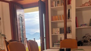 A dining table with breakfast items, a bookshelf, and a view of mountains.