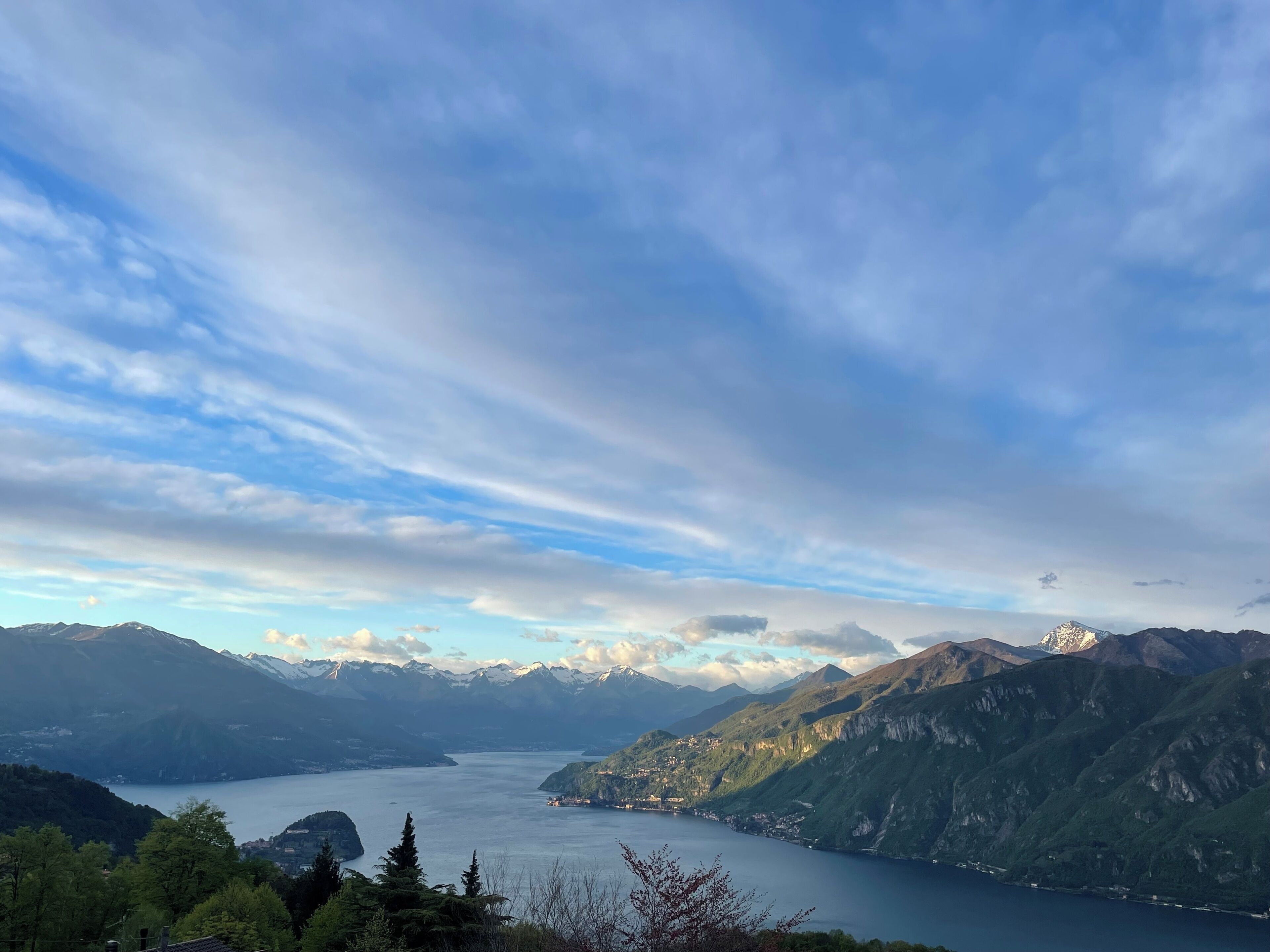 Une vue panoramique d’un paysage montagneux avec un lac et, au loin, des sommets enneigés.