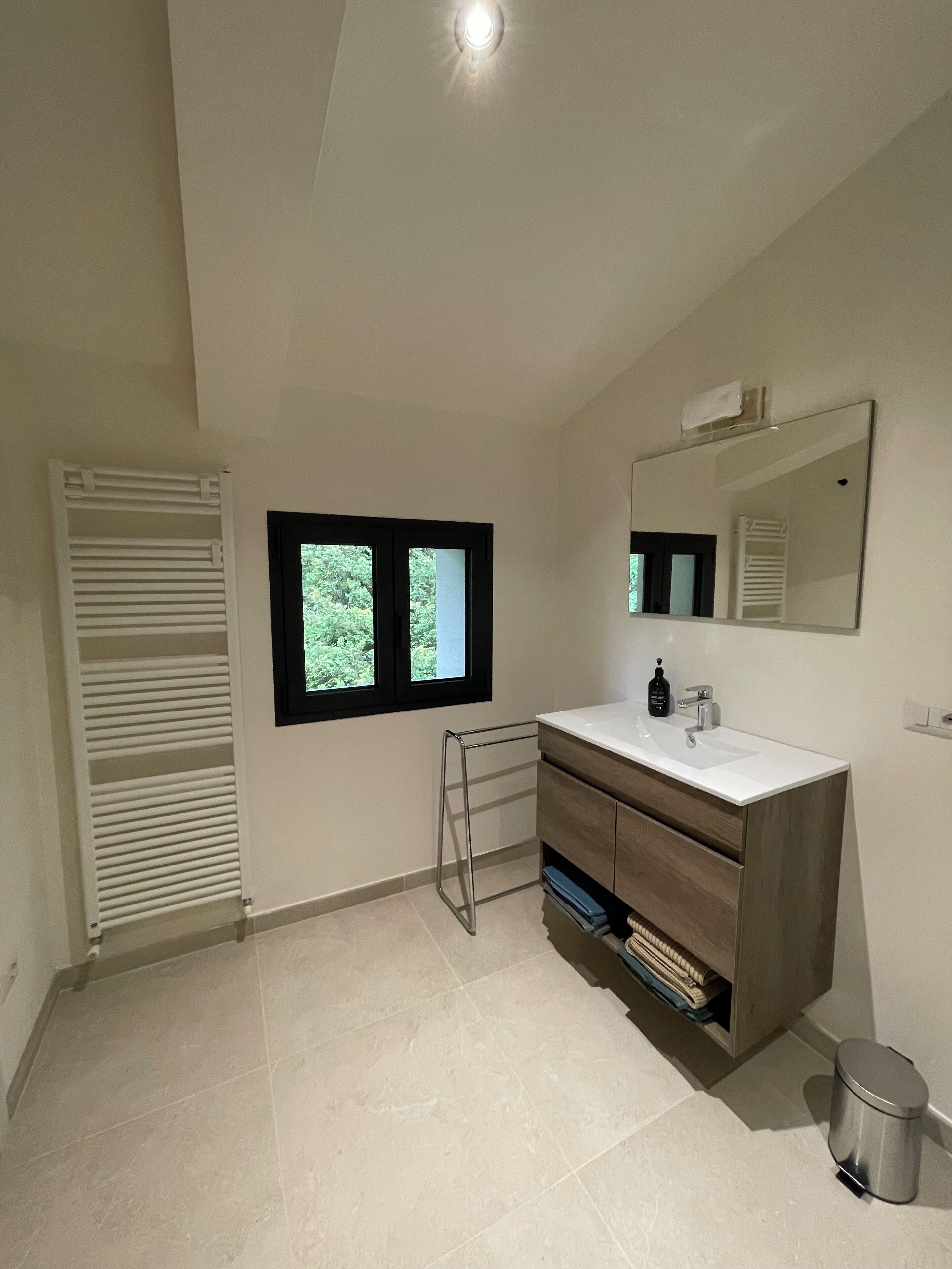 Uma casa de banho moderna com uma toucador branco, um espelho e uma janela.