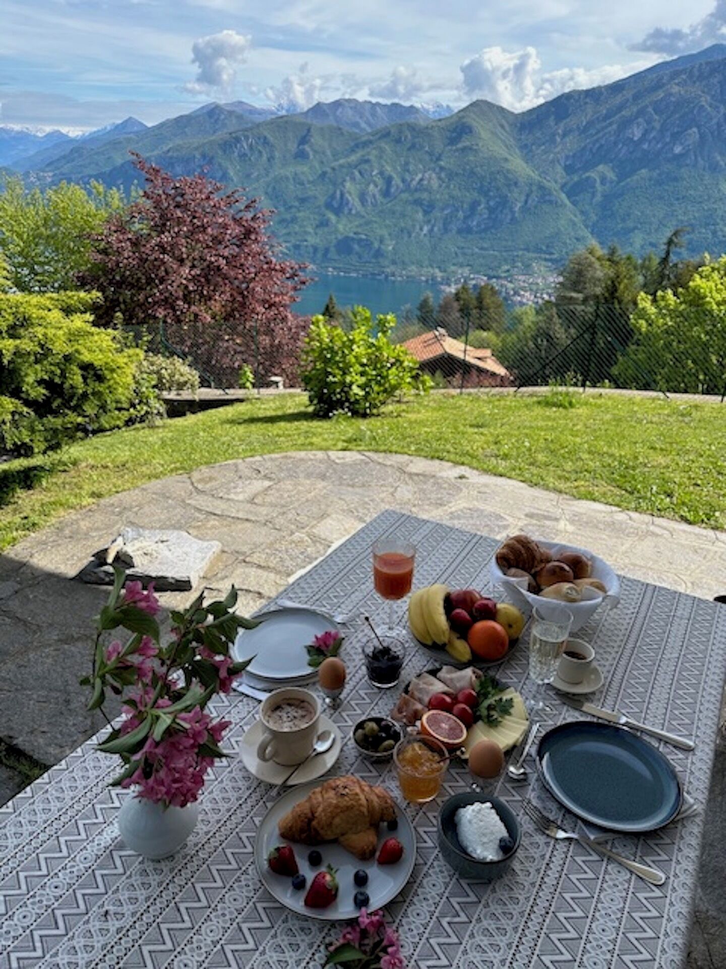 Un espace de restauration en plein air, avec une table dressée pour le petit-déjeuner, entouré de montagnes et de verdure.