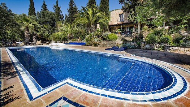 A swimming pool with a tiled edge, surrounded by lush greenery and a stone wall. - Ottoman Villa - Five Bedroom Villa, Sleeps 10 (Yalıkavak Mahallesi)