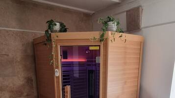 Una habitación con sauna, paredes de madera, una silla blanca y una planta en maceta.