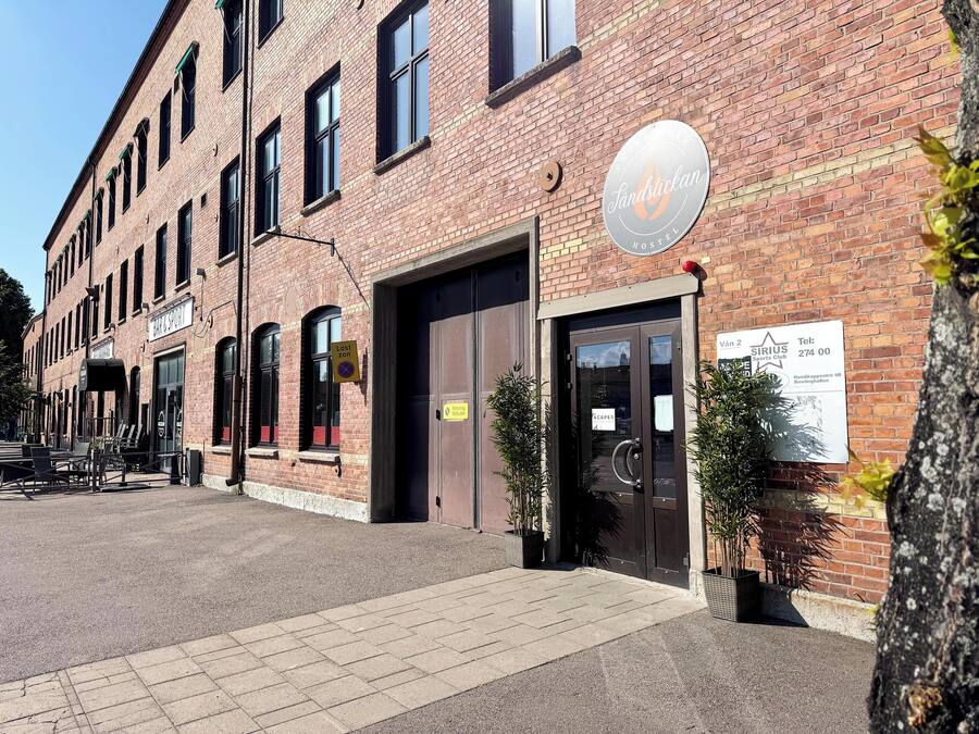 A brick building with a sign for 'Sandstickan Hostel' and a sports club named 'Sirius Sports Club'.
