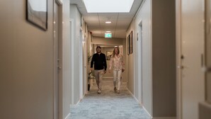 A hallway with a carpeted floor, framed pictures on the walls, and a ceiling light. - My Hostel Lidköping (Lidköping)