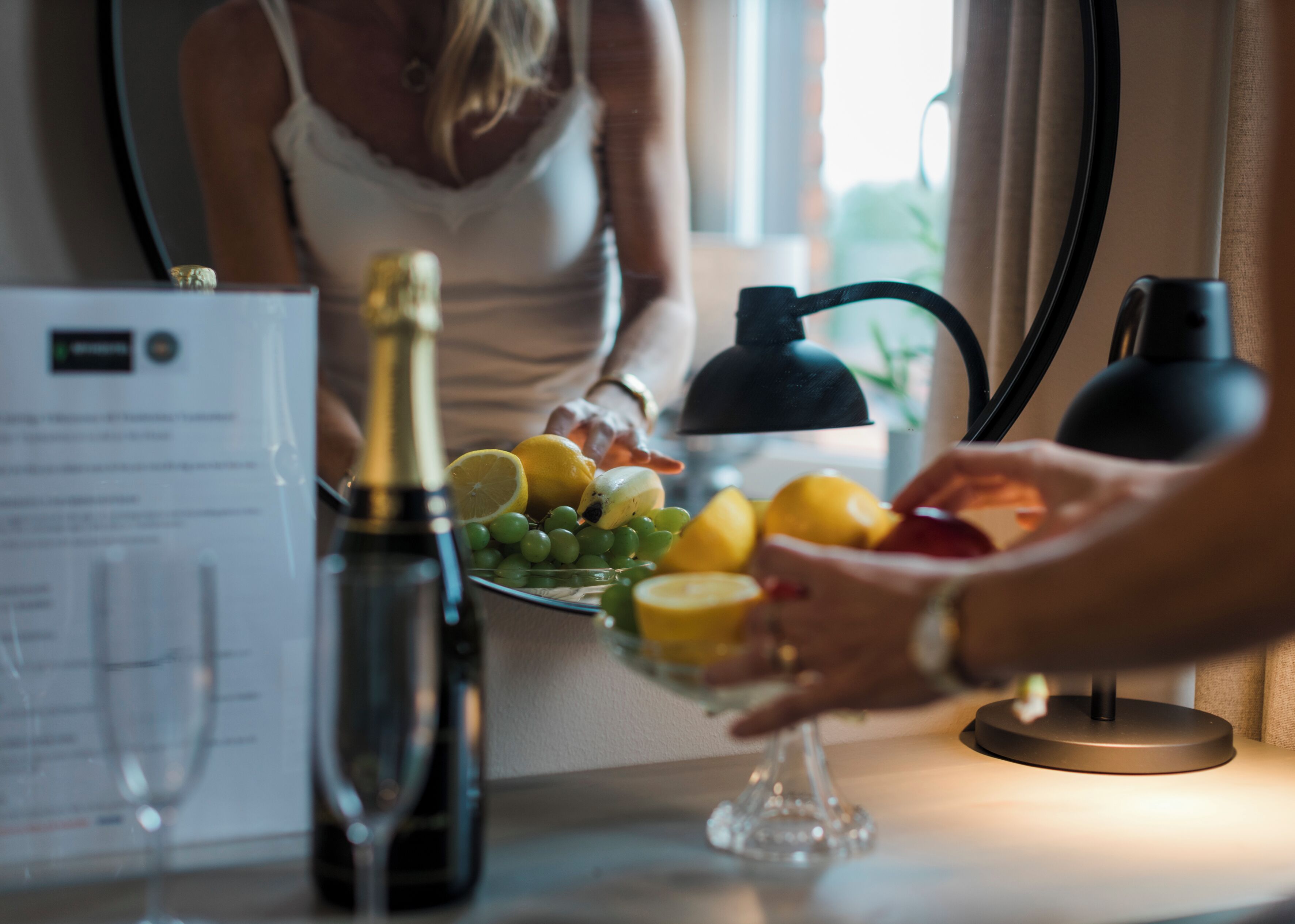 Une table avec une bouteille de champagne, un verre et une assiette de fruits.