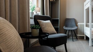 A modern, well-lit room with a black chair, a grey armchair, a small table with a plant, and a white radiator. - My Hostel Lidköping (Lidköping)