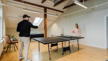 Una mesa de ping pong en una habitación con pisos de madera y techo inclinado.