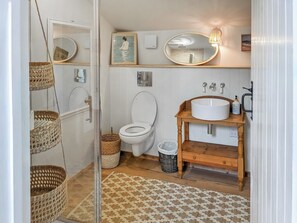 A bathroom with a toilet, a sink, a mirror, and wicker baskets. - Relax, switch off, and reconnect in this inviting Shropshire studio. (Shrewsbury)