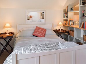 A neatly arranged bedroom with a bed, two bedside tables with lamps, a bookshelf, and a mirror on the wall. - Relax, switch off, and reconnect in this inviting Shropshire studio. (Shrewsbury)