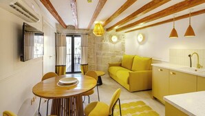 A compact living space with a dining area, sofa, kitchen, and a stone wall.