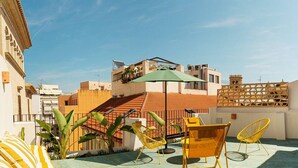 A rooftop terrace with a green umbrella, yellow chairs, and potted plants. - Apt Charme Exceptionnel Alicante (Alacant)