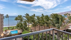 Un balcone con vista sull'oceano, palme e una piscina.