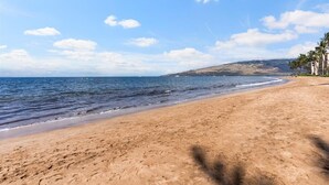 Una spiaggia con cieli sereni, acque calme e montagne sullo sfondo.