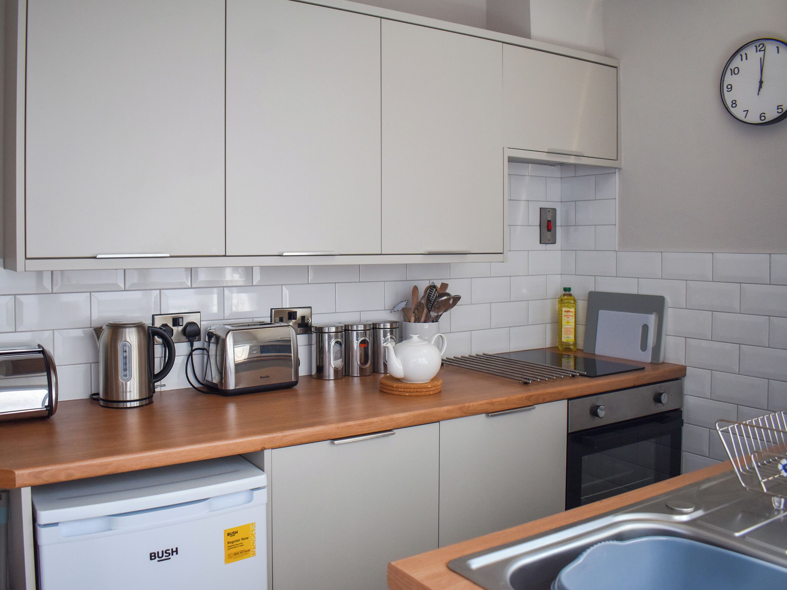 A modern kitchen with white cabinets, stainless steel appliances, and a wooden countertop.