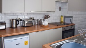 Una cocina moderna con armarios blancos, electrodomésticos de acero inoxidable y encimera de madera.