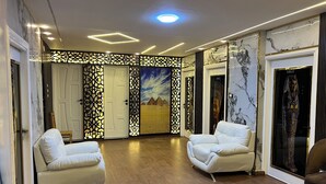 A spacious lobby with two white leather sofas, a wooden floor, and a decorative wall with a mural. - Miracle Pyramids View Hotel (Giza)
