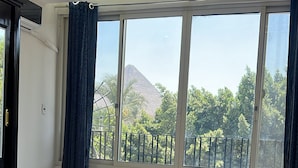 A bedroom with a large bed, a window with a view of trees and a mountain, and a ceiling with recessed lighting. - Miracle Pyramids View Hotel (Giza)