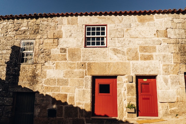 A stone building with two red doors and a small window.