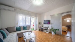 A modern living room with a sofa, coffee table, TV, and a sliding door leading to a bedroom.