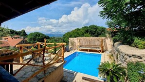 A pool area with a wooden deck and a view of the surrounding landscape. - The Hideaway- authentic Dalmatian stone house with a pool Hvar island (Vrbanj, Hvar)