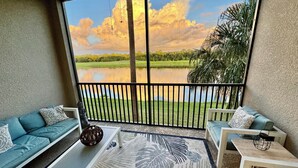 Ein Balkon mit Seeblick, einer Couch, einem Couchtisch und einem gemusterten Teppich.