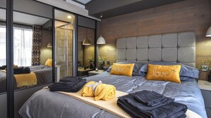 A modern hotel room with a large bed, a mirror, and a nightstand with a lamp. - 2 bedroom accommodation in St Andrews (St Andrews)