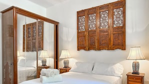 A hotel room with a large bed, two bedside tables with lamps, a wooden wardrobe, and a decorative wooden panel on the wall. - Prédio Vinicius  (Rio de Janeiro)