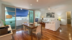 A modern living room with a wooden floor, a dining table, a white sofa, and a TV. - Prédio Vinicius  (Rio de Janeiro)