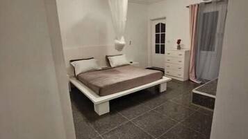 Ein Schlafzimmer mit Bett, Nachttisch, Kommode und Himmelbett.