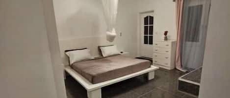 A bedroom with a bed, a nightstand, a dresser, and a canopy bed.