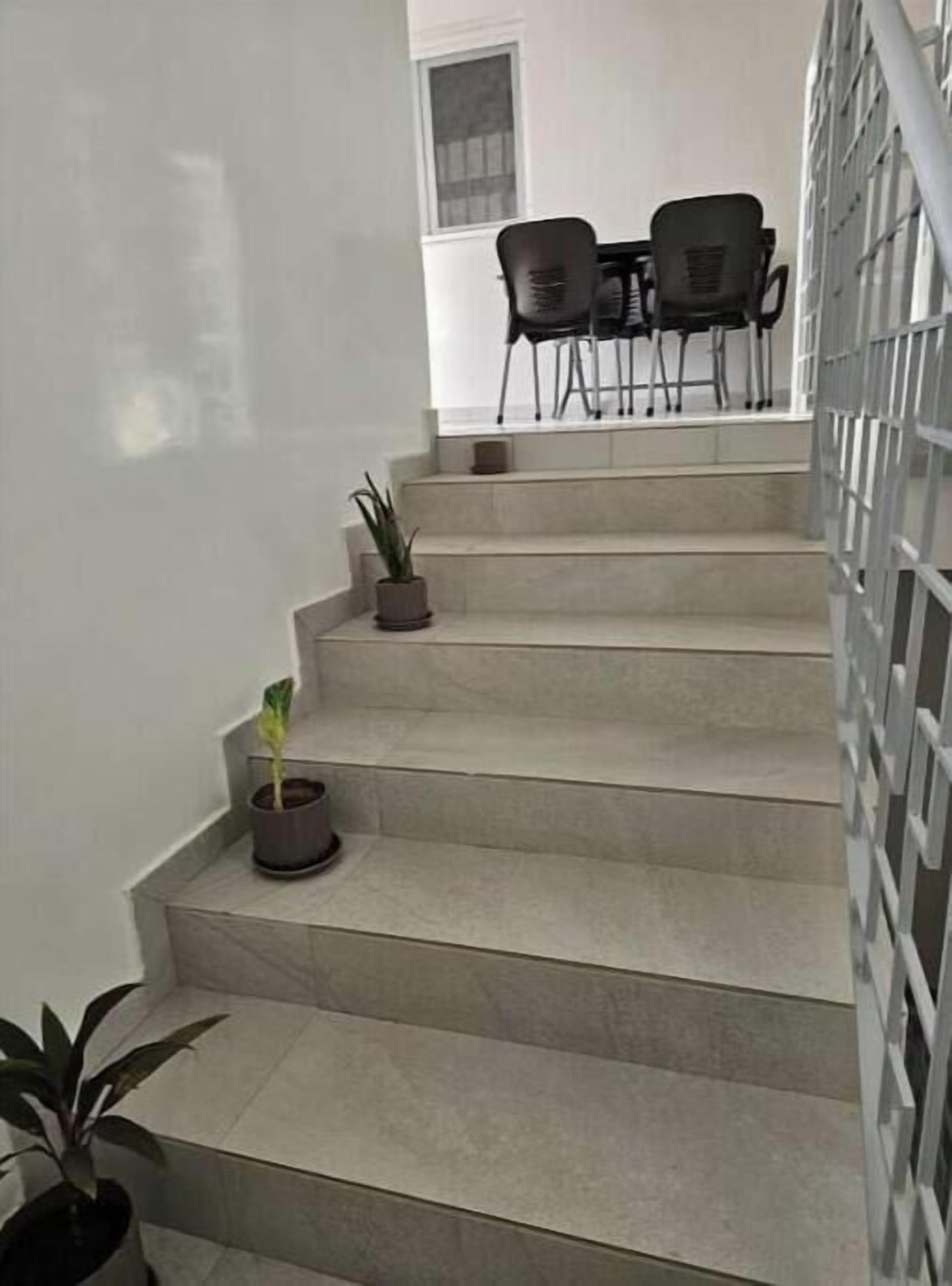 Eine Treppe mit Blumentöpfen, die zu einem Essbereich mit Stühlen und einem Tisch führt.