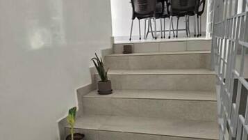 Eine Treppe mit Blumentöpfen, die zu einem Essbereich mit Stühlen und einem Tisch führt.