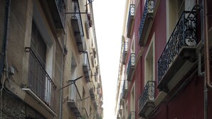 A narrow street with buildings on both sides, featuring balconies with metal railings and some greenery. - Cagliari Homes (Cagliari)