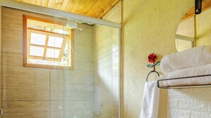 A bathroom with a wooden ceiling, a glass shower enclosure, a white toilet, and a sink with a mirror above it. - Chale 2 Familia (Angra dos Reis)
