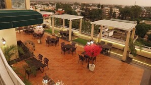 A rooftop terrace with outdoor seating and a view of the cityscape. - Comfort Hotel GMS Grand  (Dehradun)