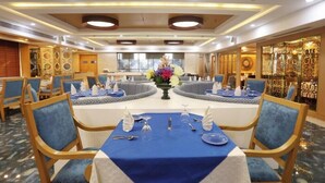 A hotel dining area with round tables, blue tablecloths, and blue chairs. - Comfort Hotel GMS Grand  (Dehradun)