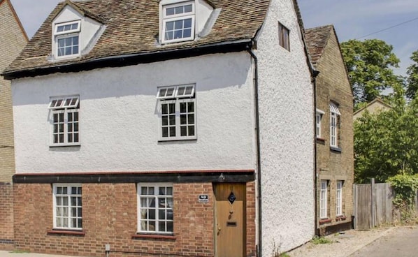 A two-story building with a white exterior, multiple windows, and a brick base. - 4 BR & 2 Bathroom House Parking Garden St Neots Town Centre (St Neots)
