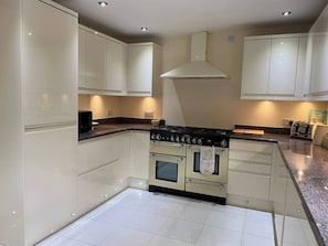 A kitchen with white cabinets, a stove, oven, and a tiled floor. - 4 BR & 2 Bathroom House Parking Garden St Neots Town Centre (St Neots)